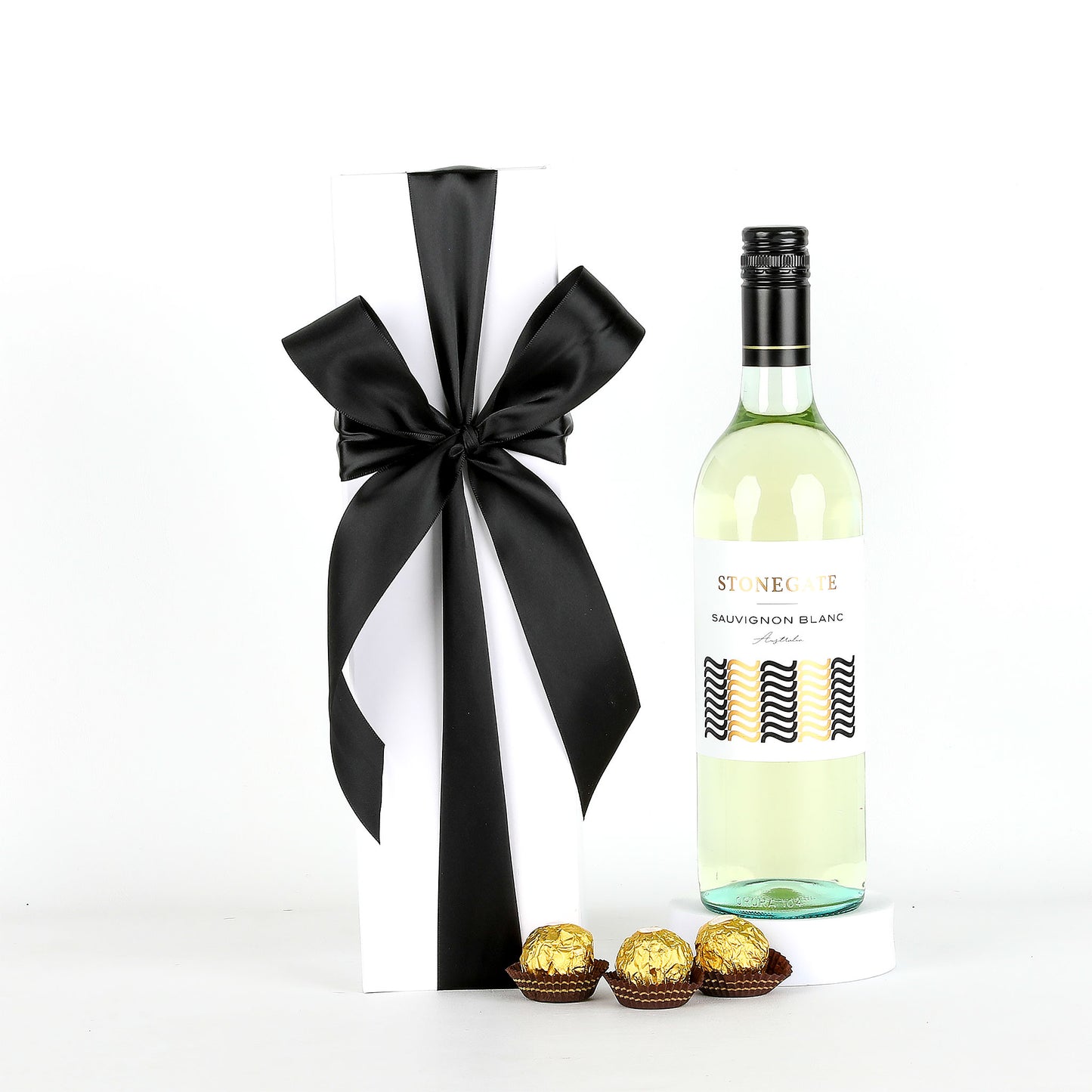 Bottle of white wine with a black ribbon and Ferrero Rocher chocolates on a white background