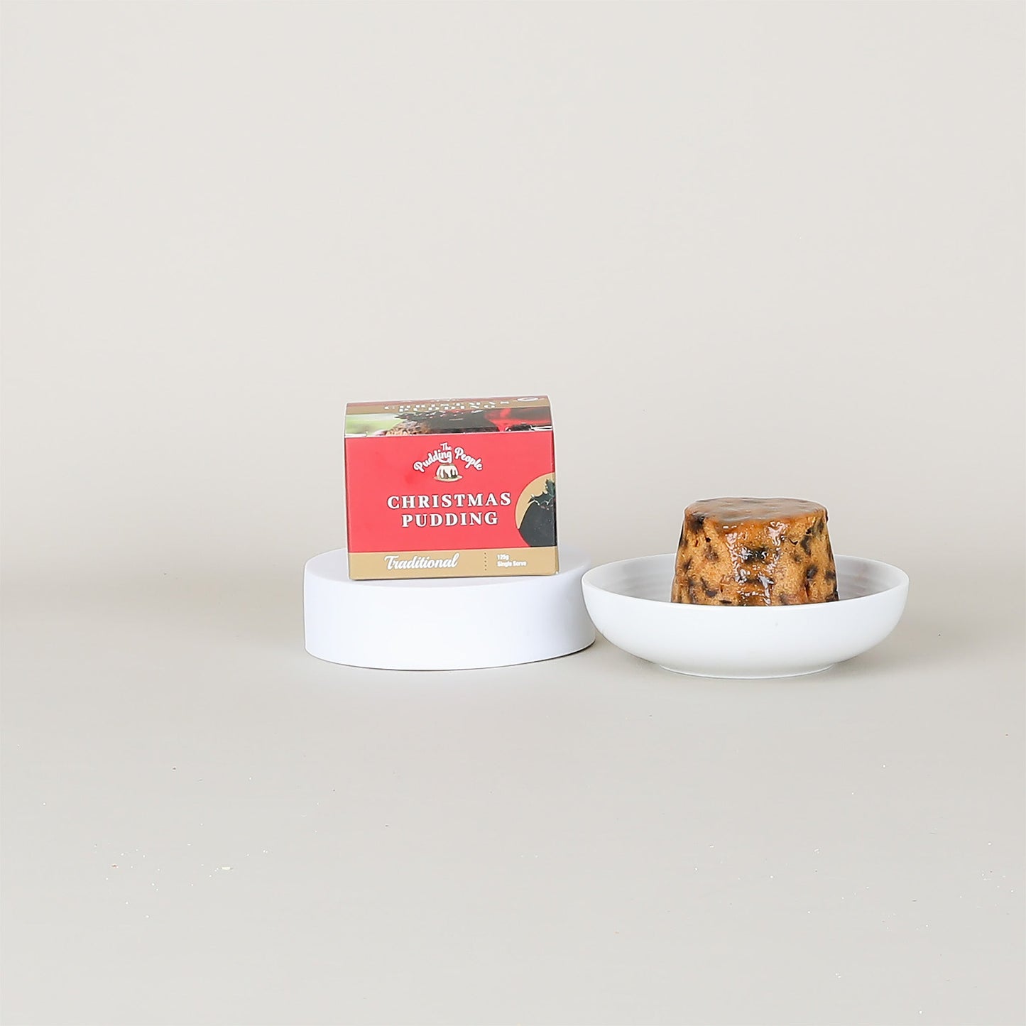Christmas pudding in a bowl with a box labeled 'Christmas Pudding' on a light grey background