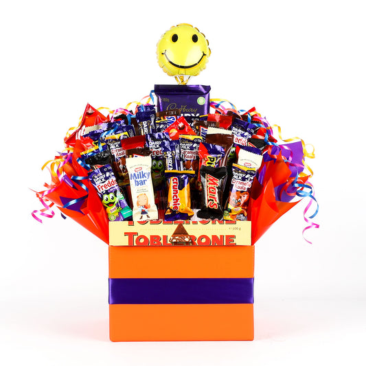 Colorful gift box filled with various chocolates and a happy-themed balloon on a white background
