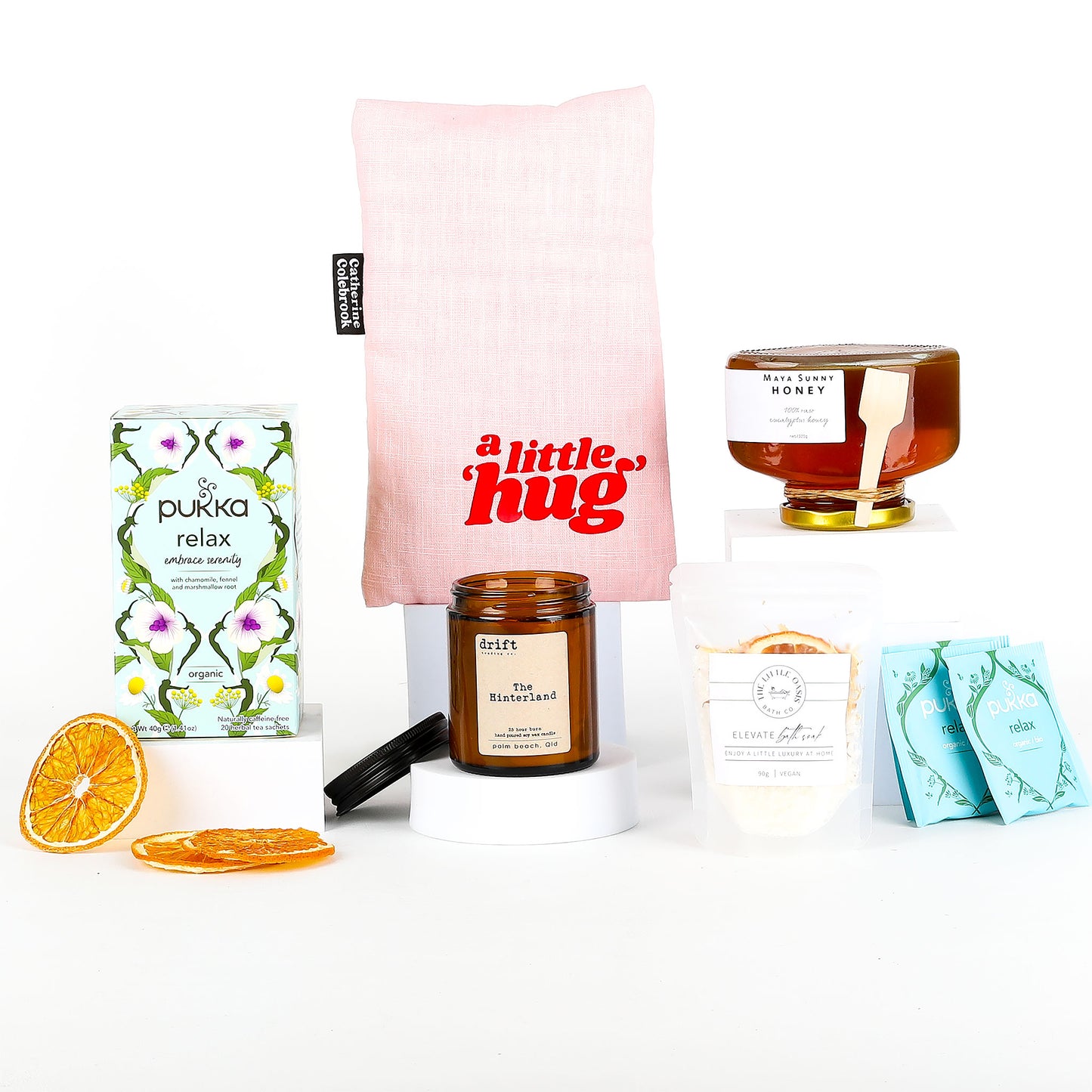Collection of self-care items including candle, a tea box, and a pillow on a white background